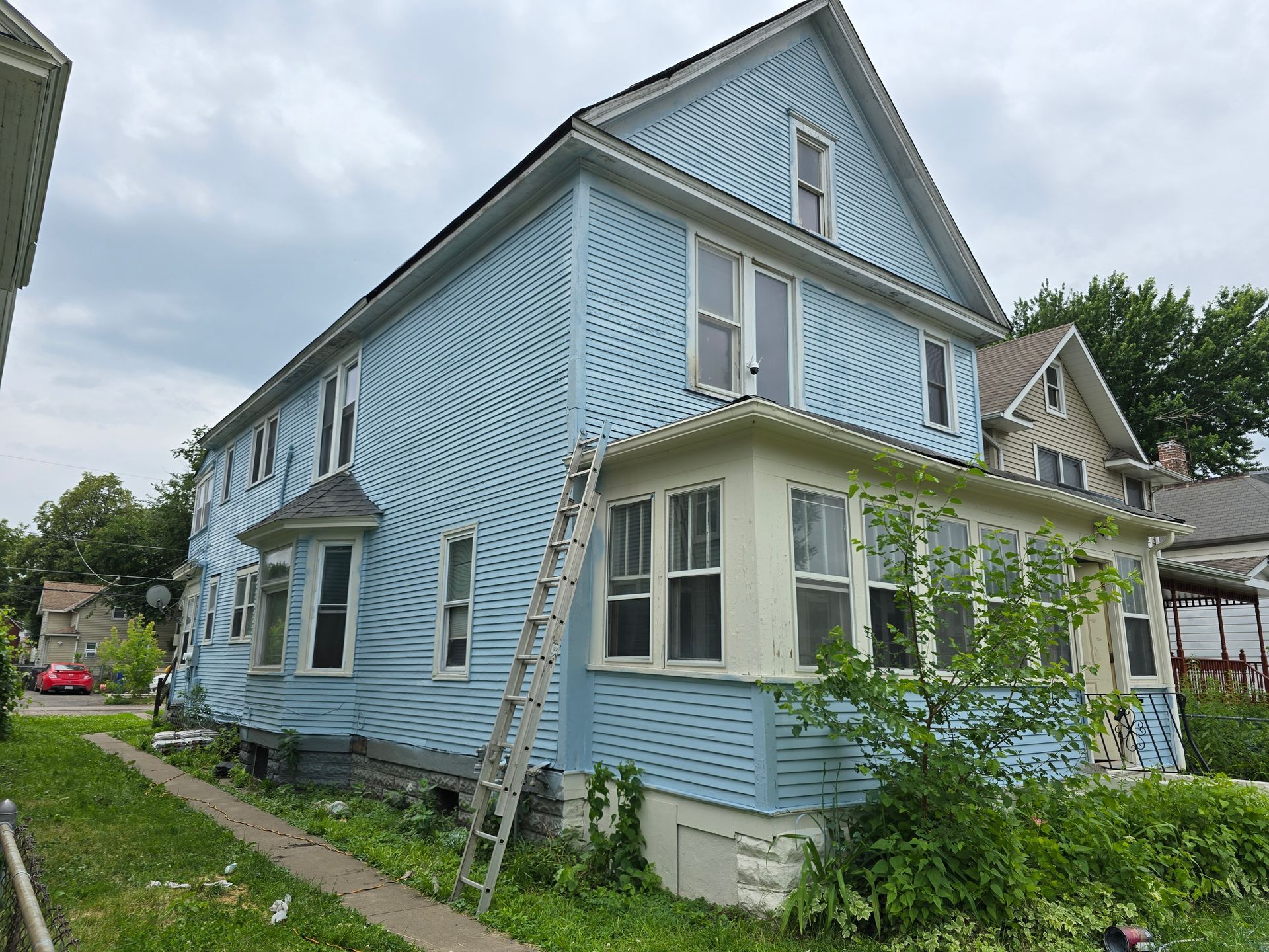 A blue and white house with a ladder on the side of it.