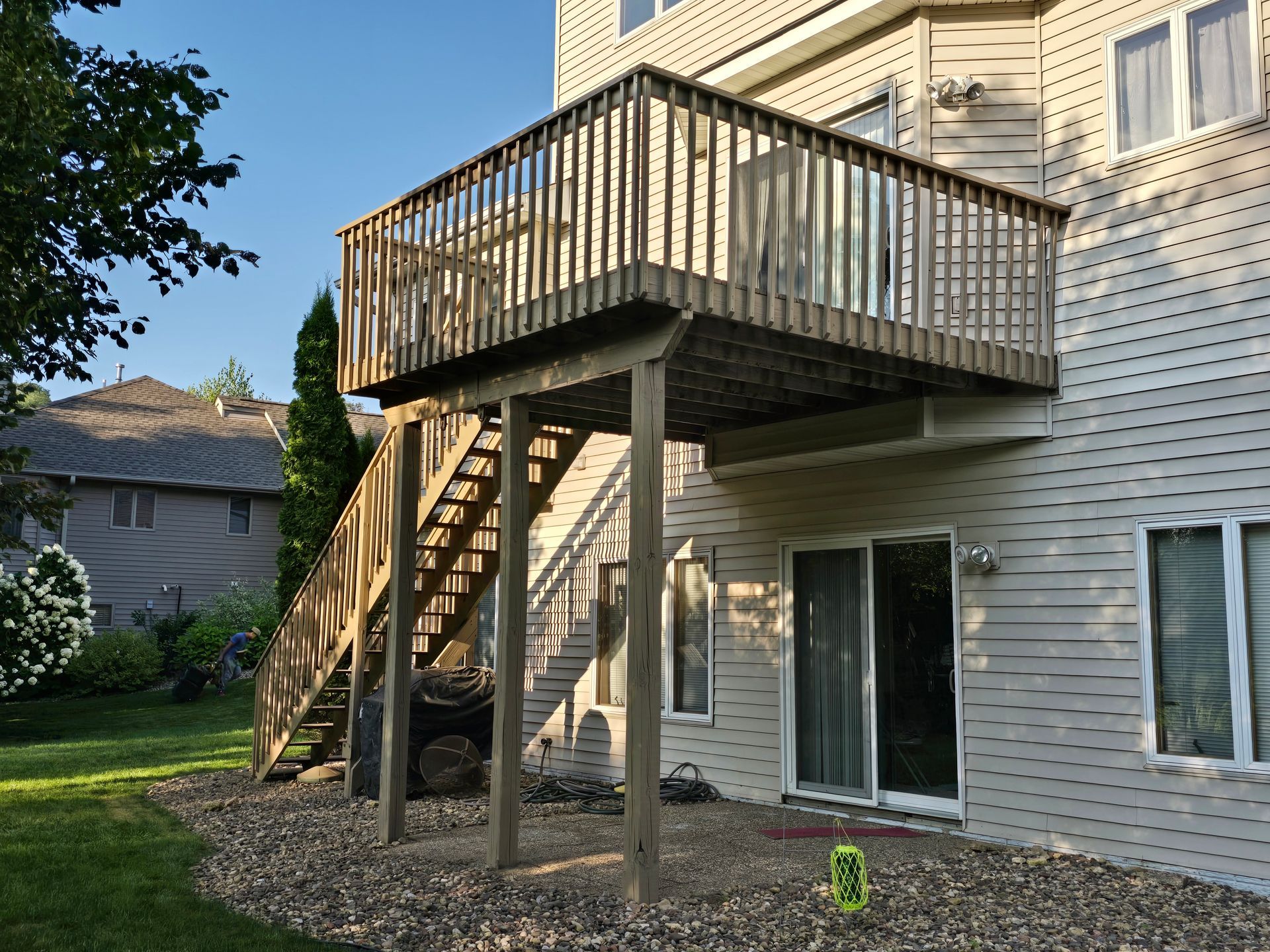 A large white house with a wooden deck and stairs.