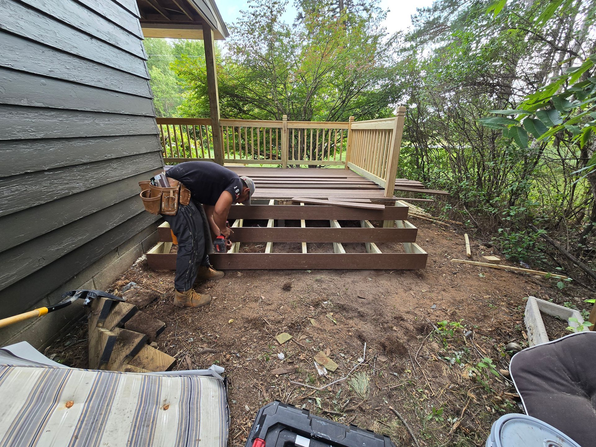 A man is working on a wooden deck in front of a house.