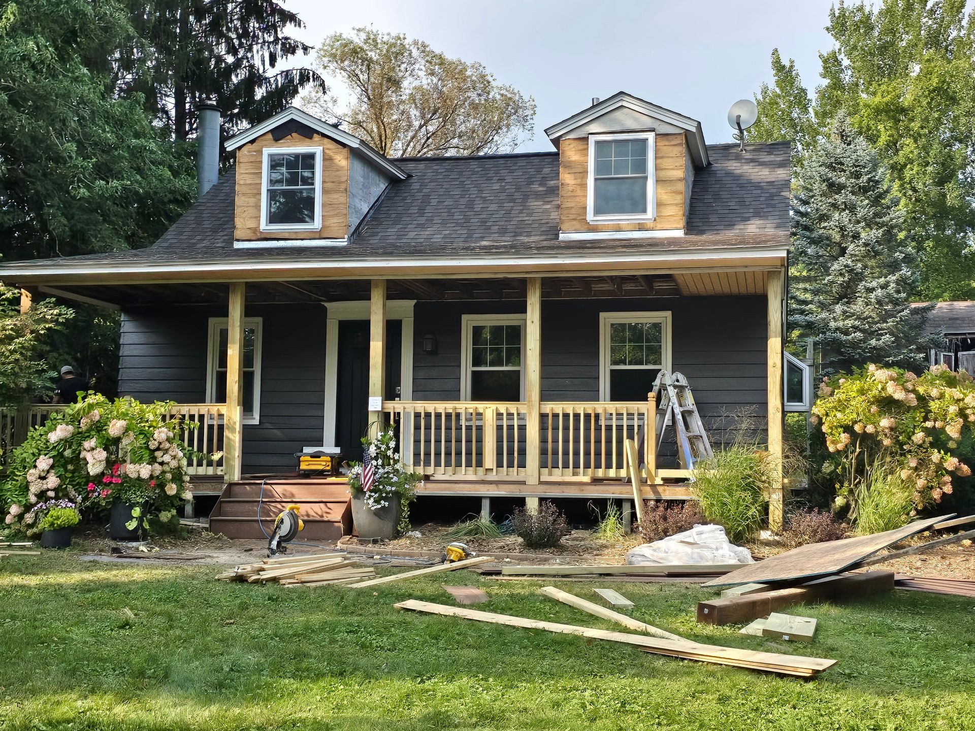 A black house with a porch is being remodeled.