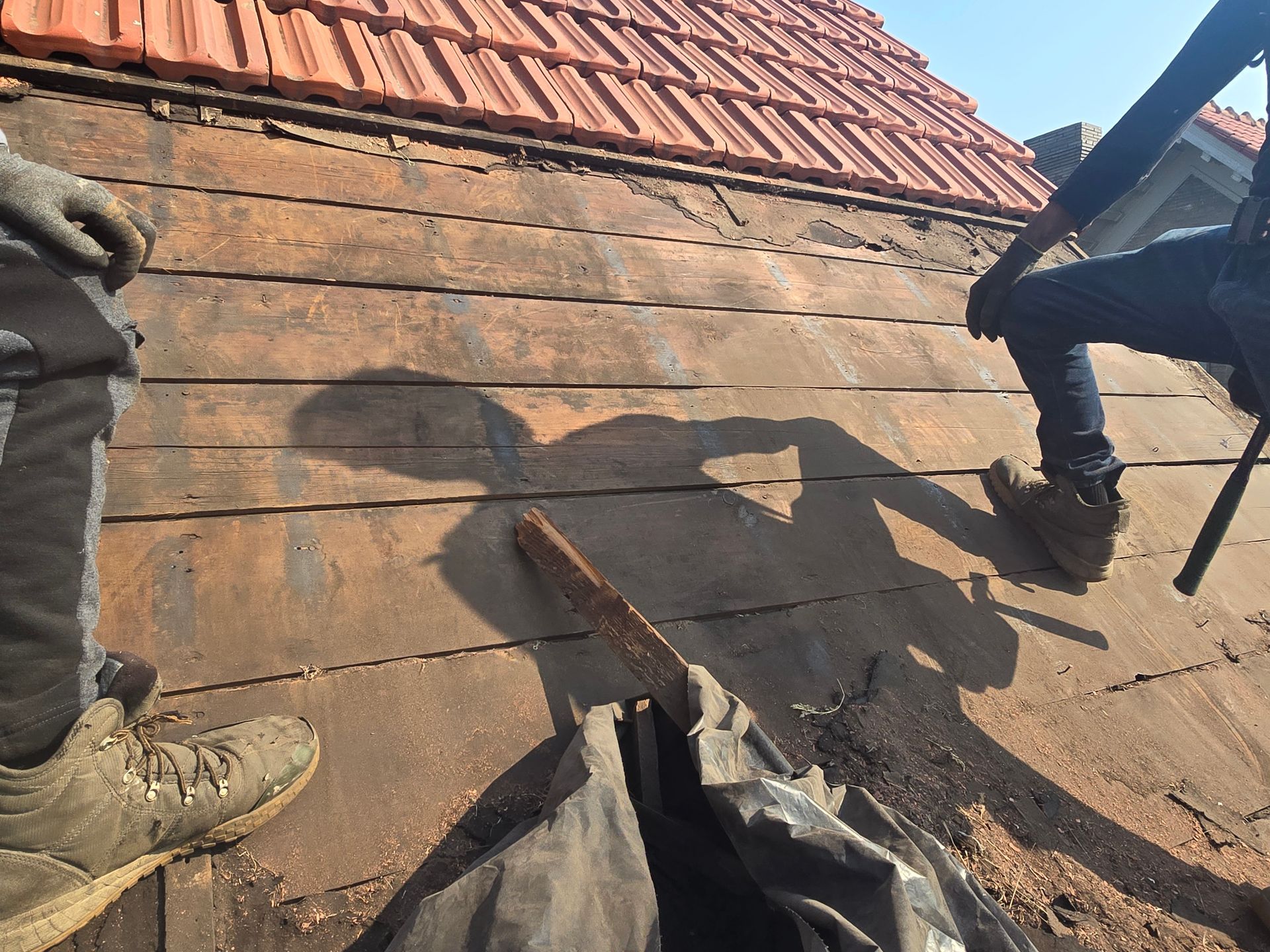 A shadow of a person is cast on a wooden roof