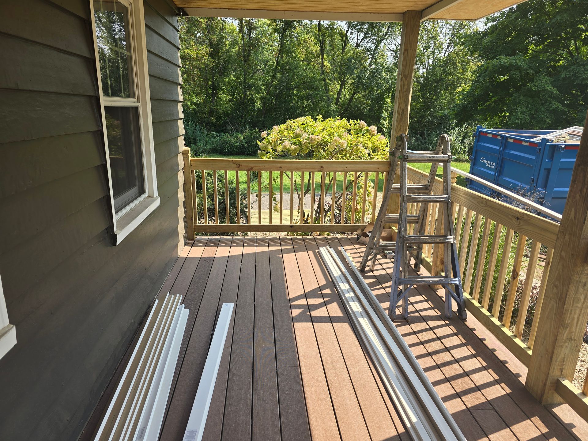 A ladder is sitting on a porch next to a window.