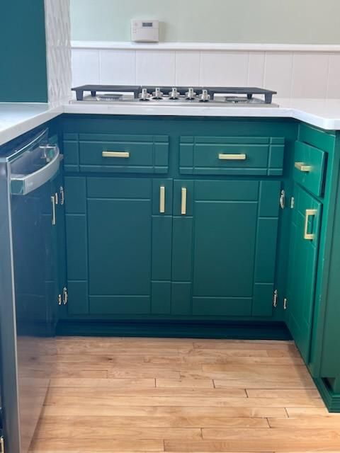 A kitchen with green cabinets and a stove top oven