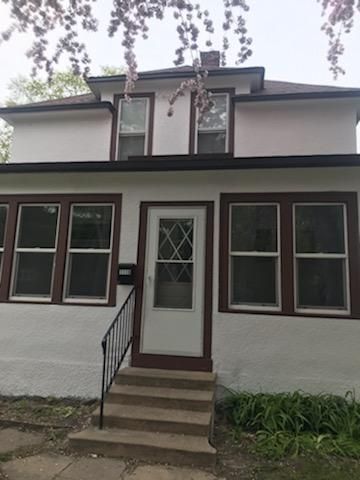 The front of a white house with brown trim and windows.