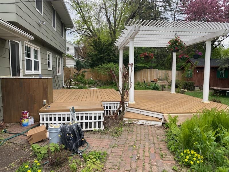 A wooden deck with a pergola in the backyard of a house.