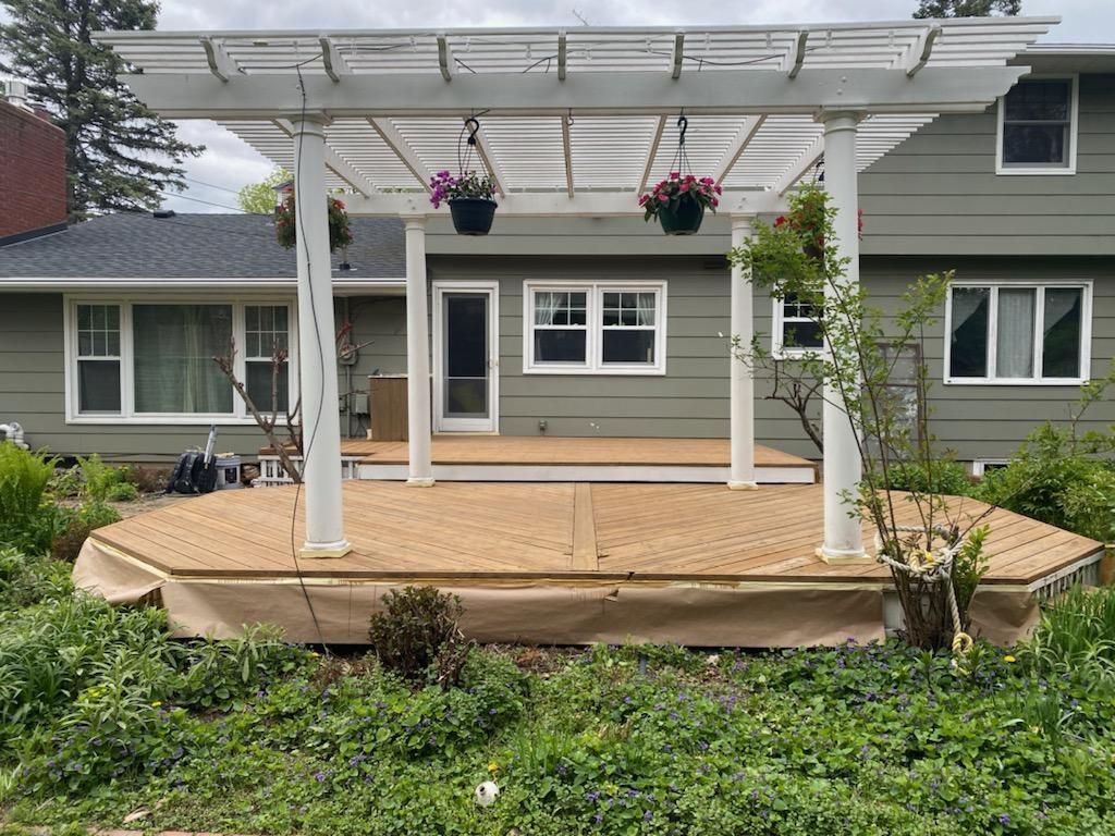 A house with a pergola and a wooden deck in front of it.