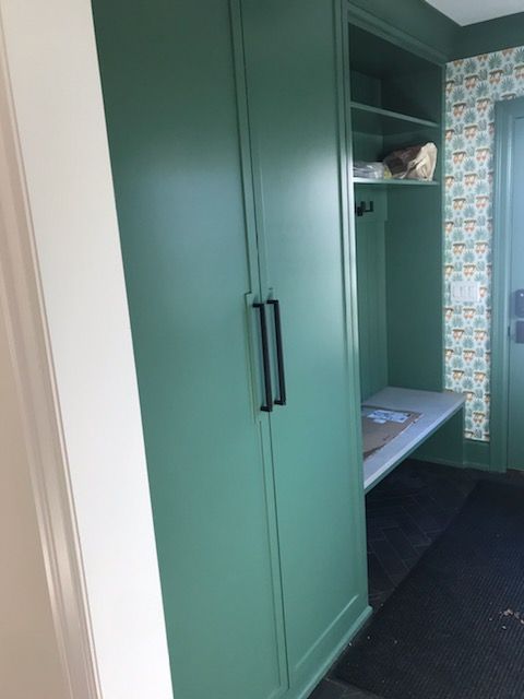 A hallway with green cabinets and a bench