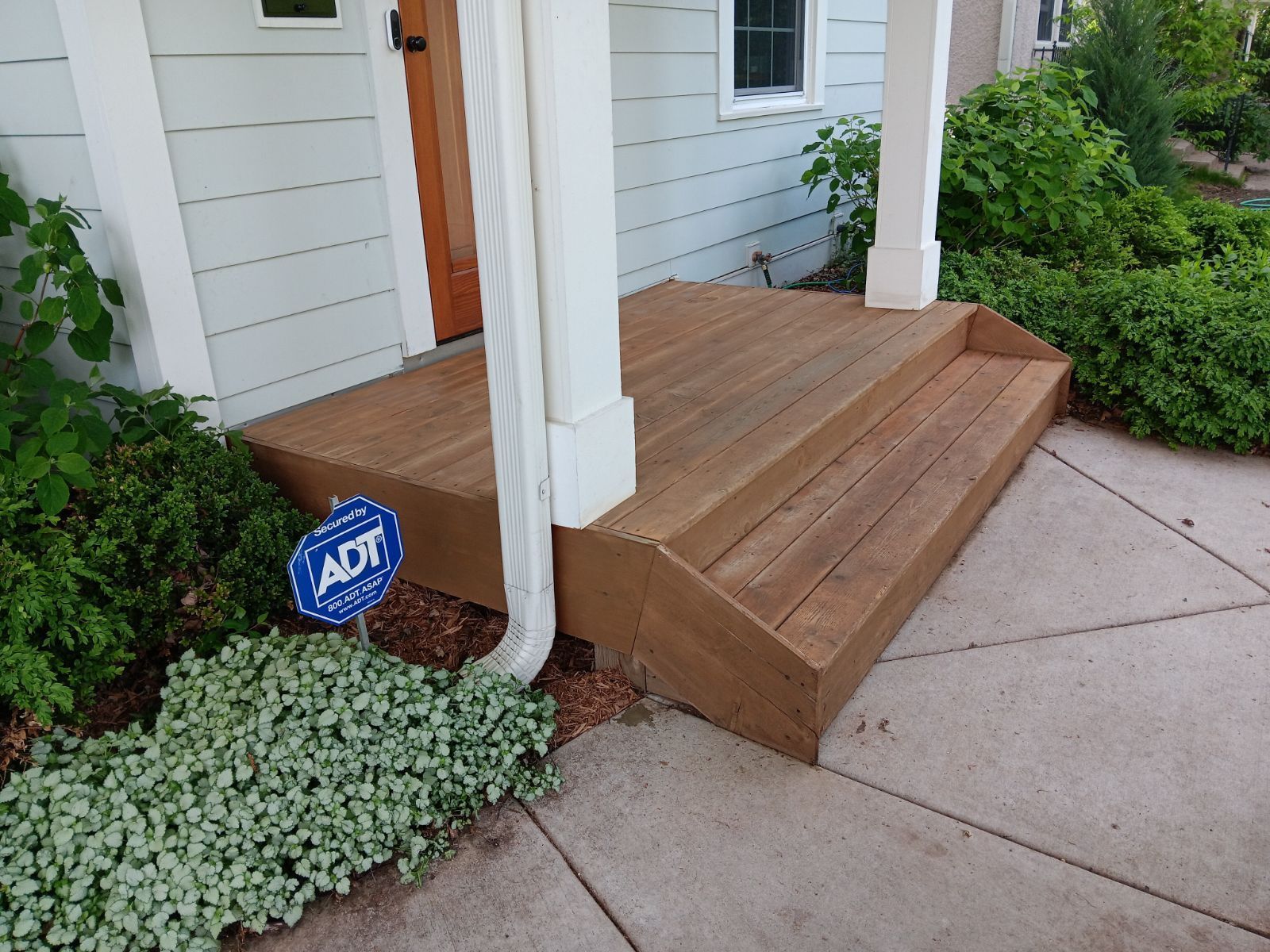 A wooden porch with a sign that says adt on it