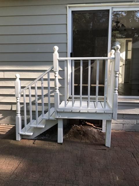 A white deck with stairs and a sliding glass door