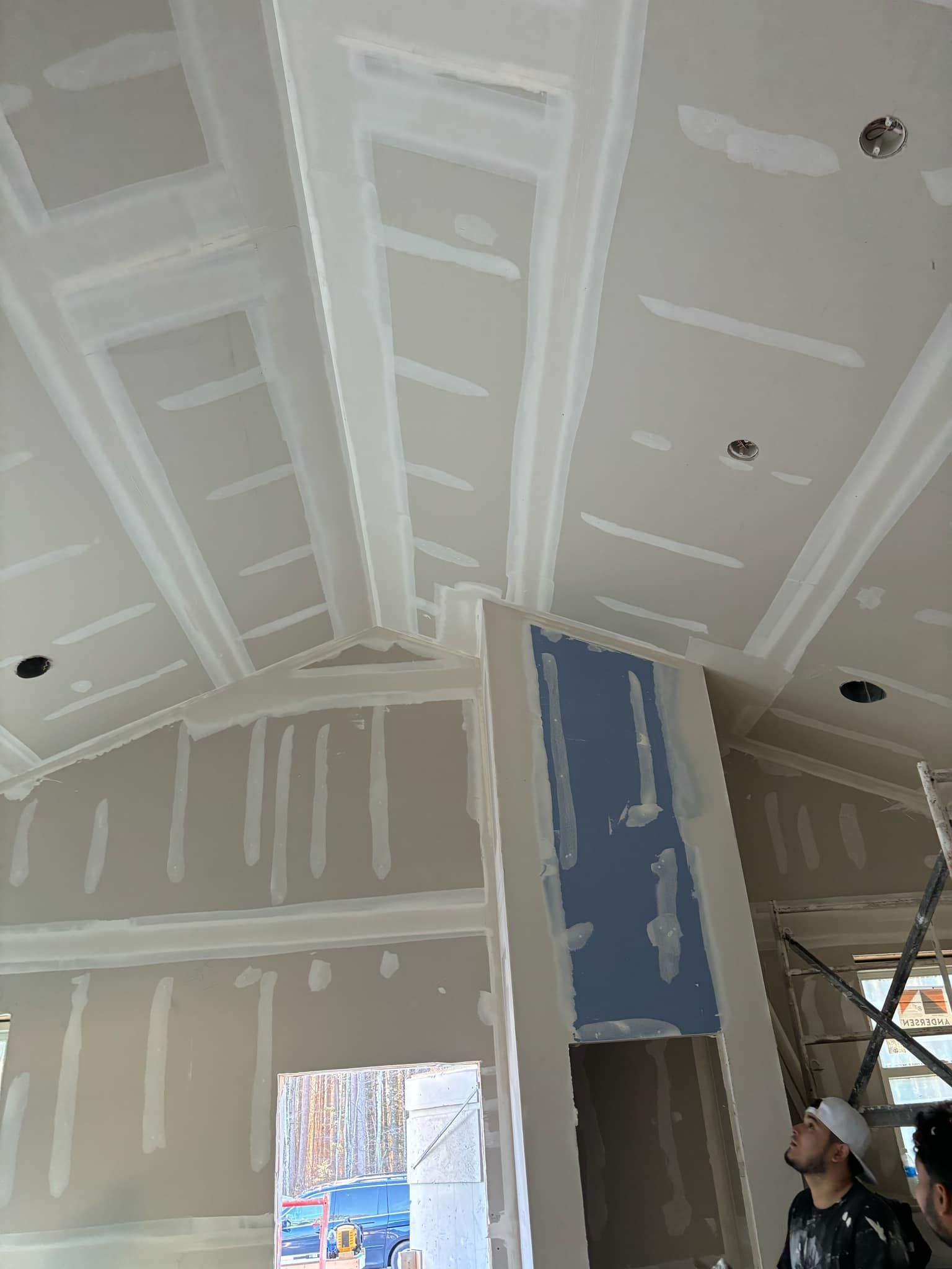 A man is standing in a room with a ceiling that is being built.