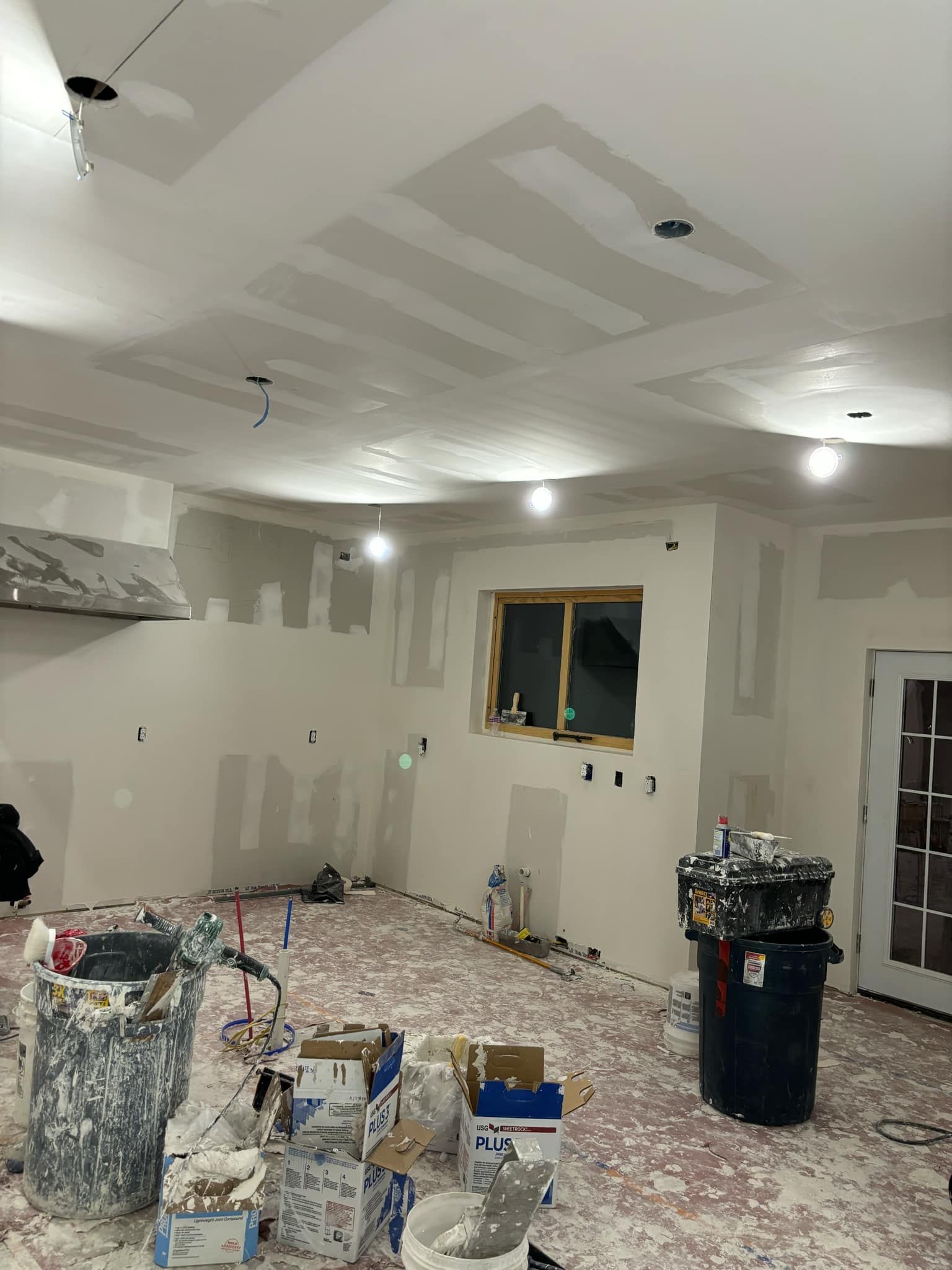 A room that is being painted with boxes of paint on the floor.