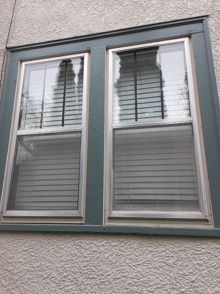 A window with blinds on it is on the side of a building.