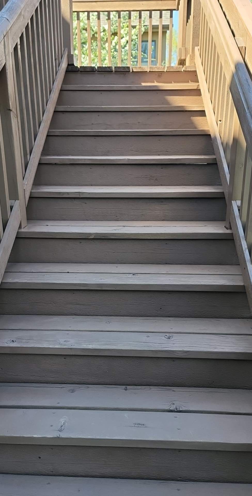 A set of wooden stairs leading up to a deck with a railing.