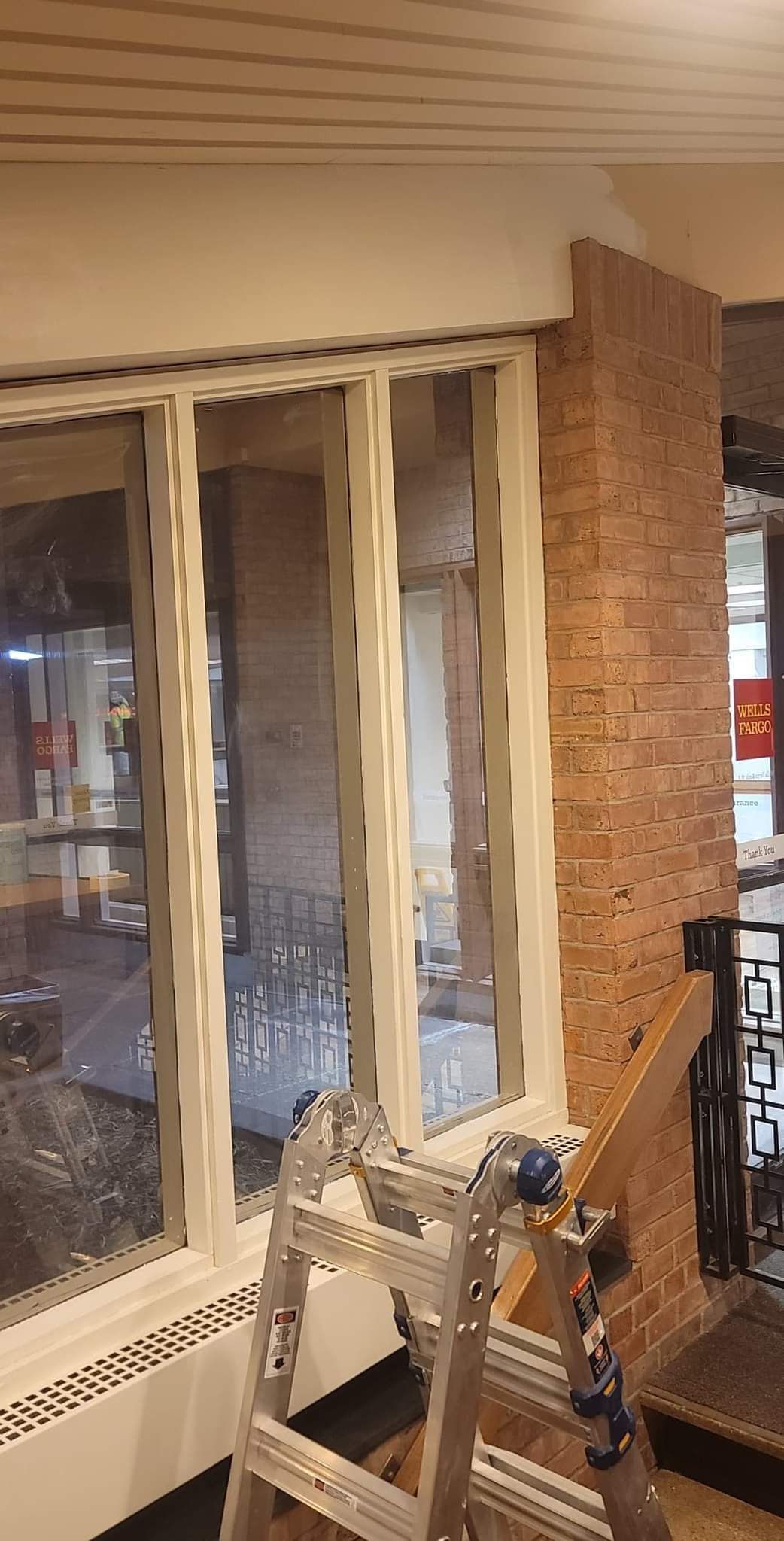 A ladder is sitting in front of a window in a room.