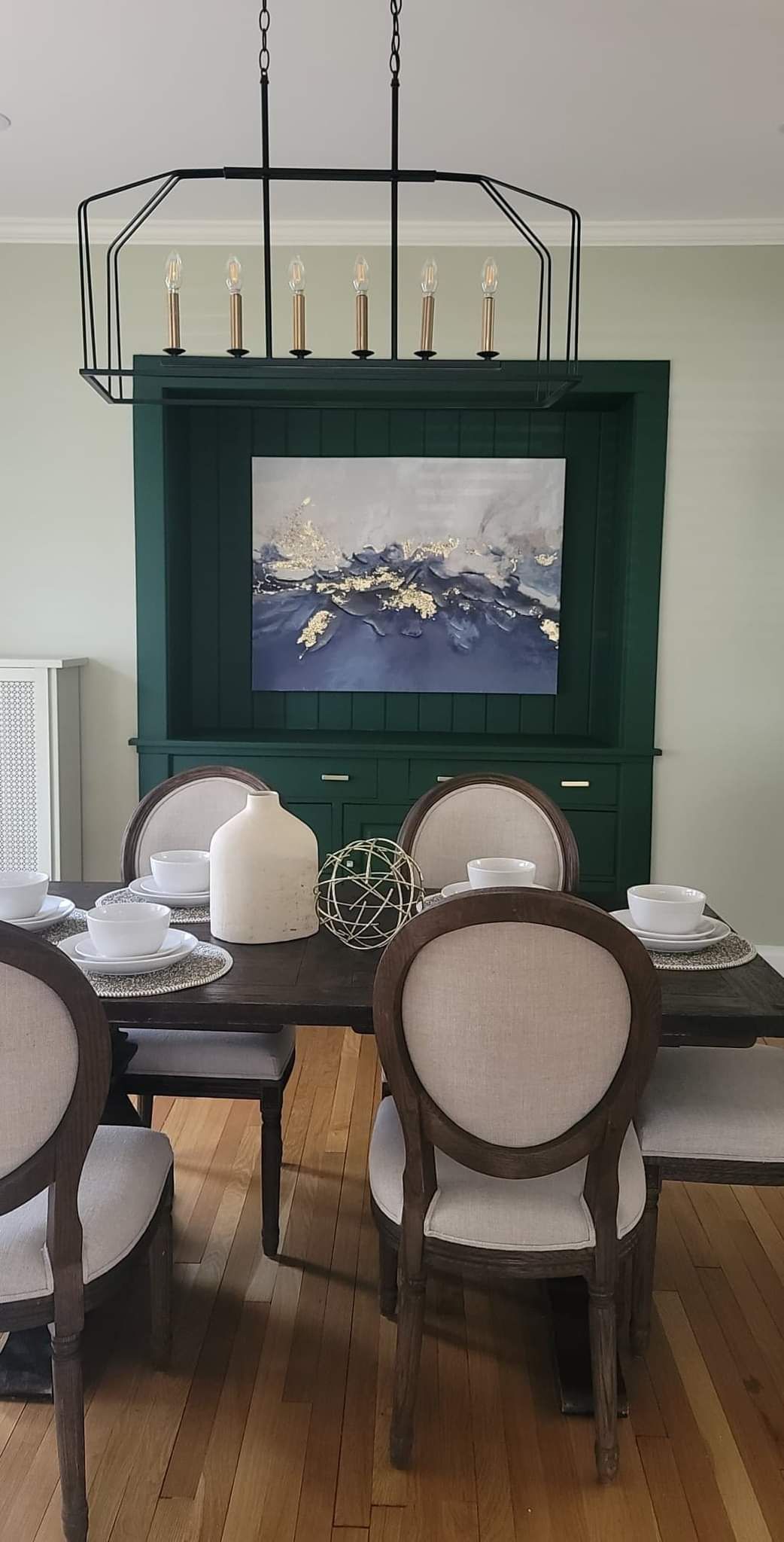 A dining room with a table and chairs and a television on the wall.