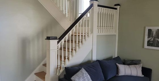 A living room with a couch and stairs leading up to the second floor.