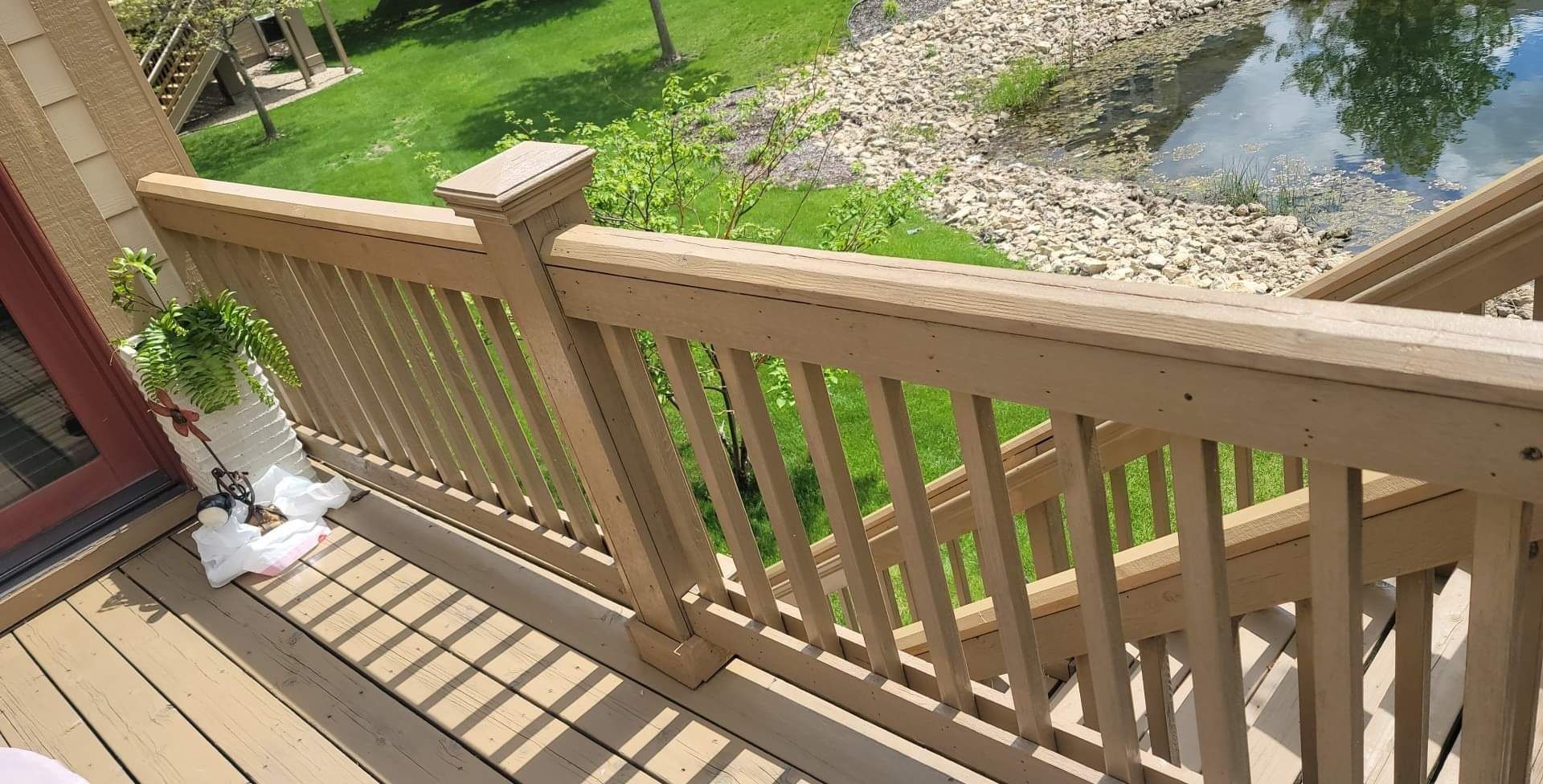 A wooden deck with a railing overlooking a river.