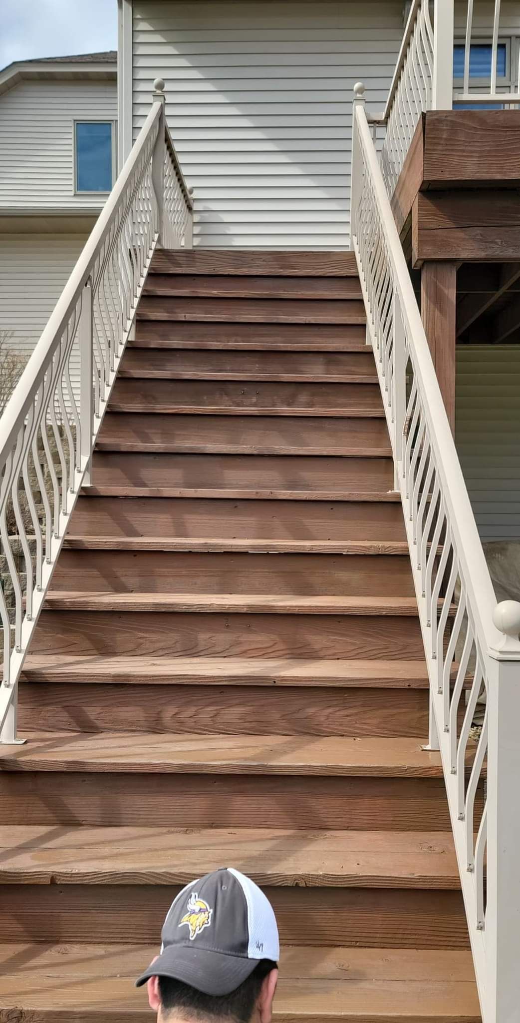 A man is standing on a set of wooden stairs leading up to a house.