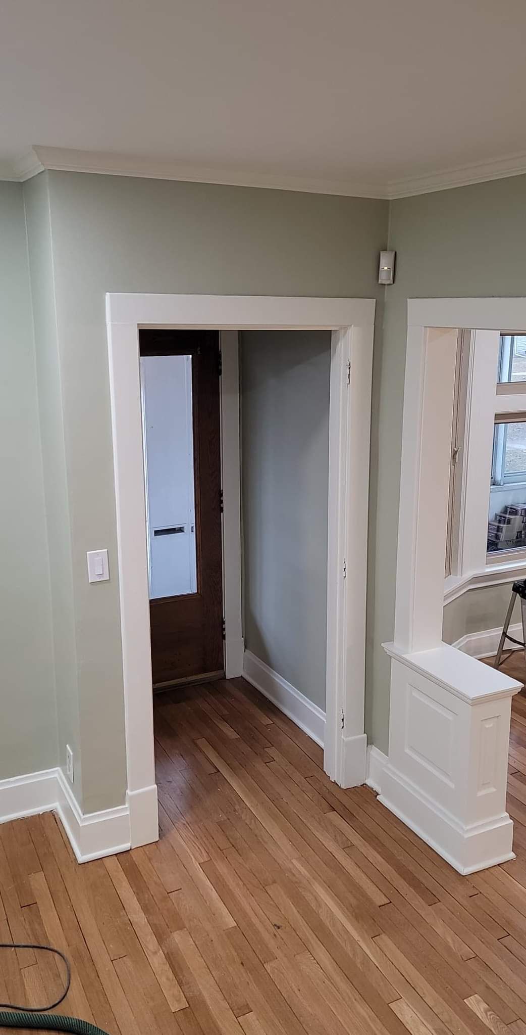 A living room with hardwood floors and a doorway leading to a hallway.