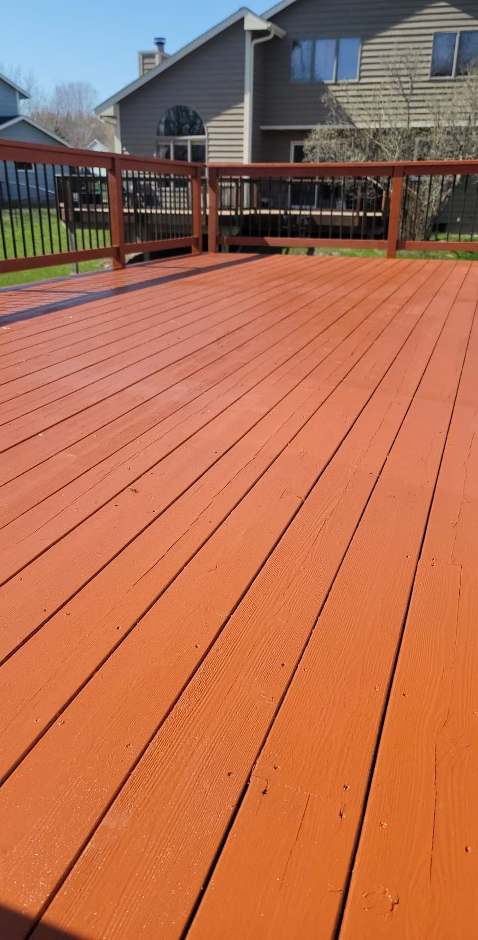 A red wooden deck with a house in the background.