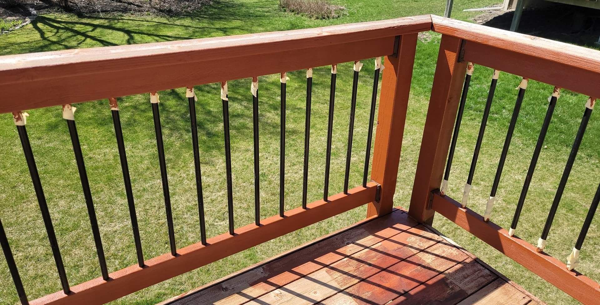 A wooden deck with a metal railing is sitting on top of a lush green lawn.