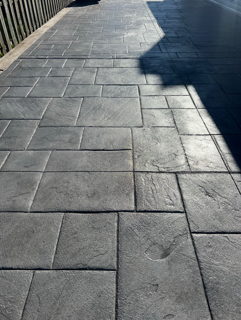 Stamped concrete sidewalk in grey rectangular stone pattern.