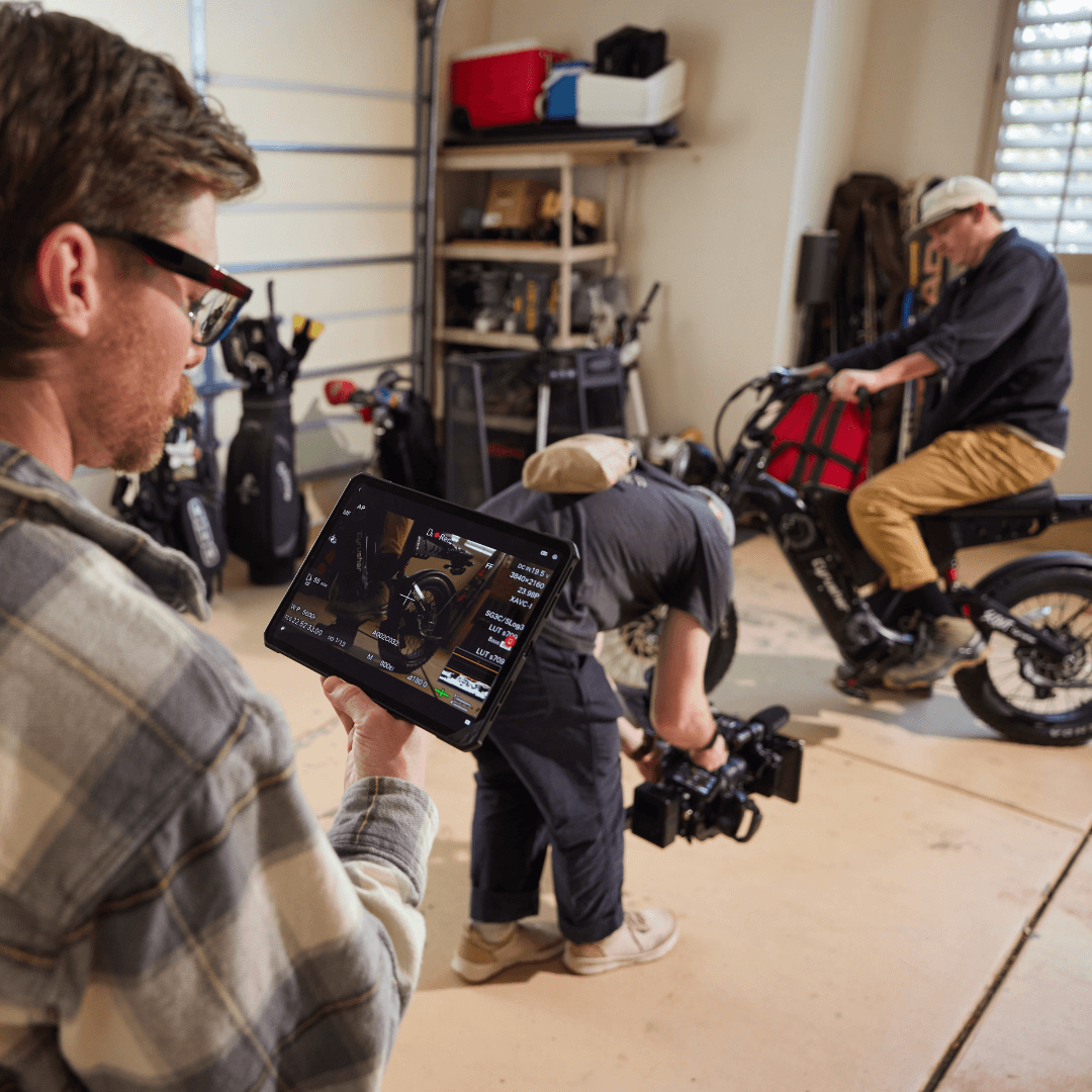 A man is holding a camera on a tripod in a living room.