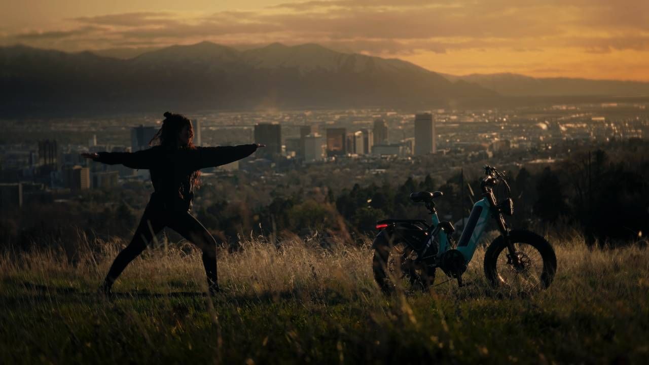 Cyclist riding an e-bike through mountain roads at sunrise.