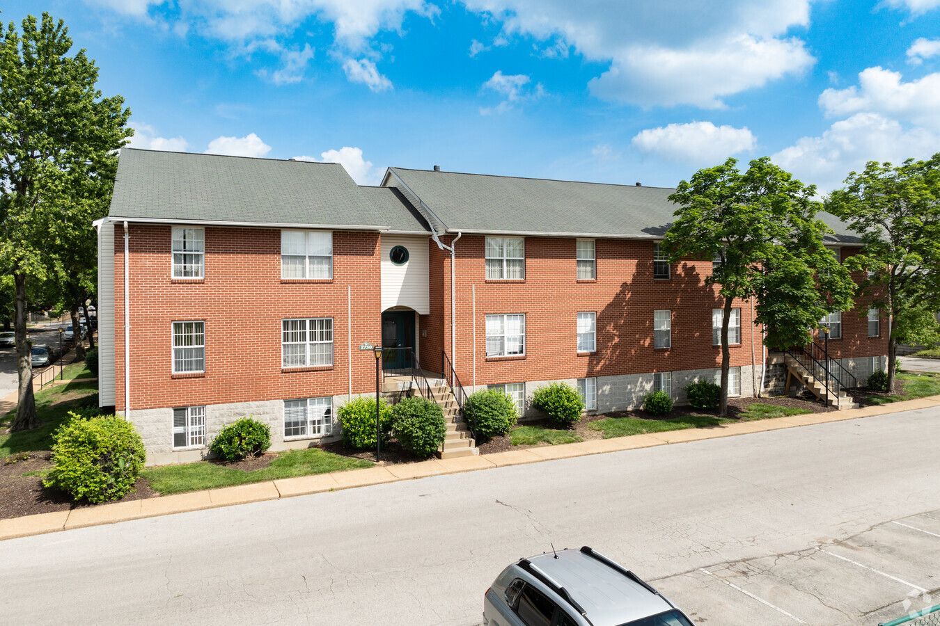 A brick apartment building with a car parked in front of it.