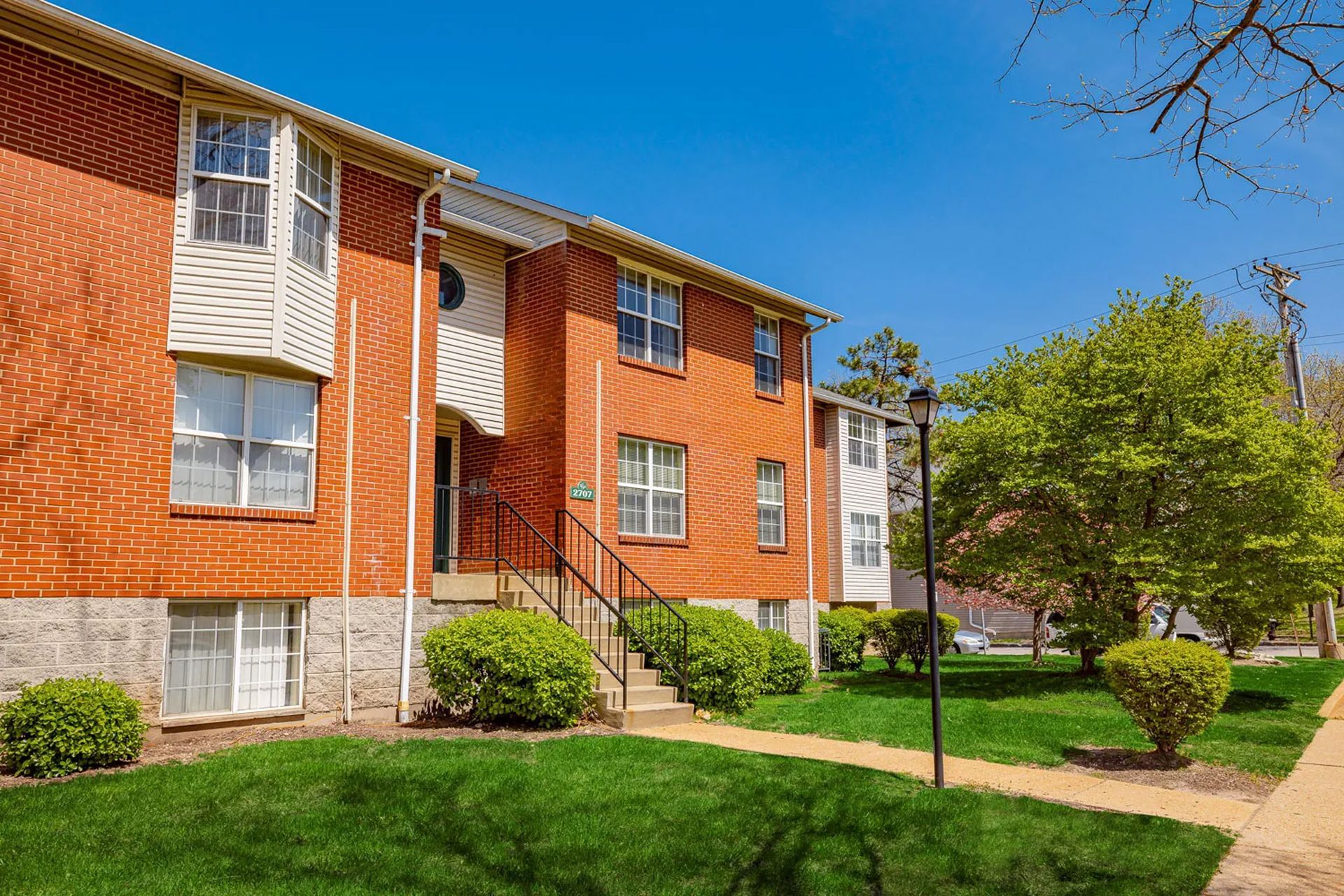 A brick apartment building with stairs leading up to the front door.
