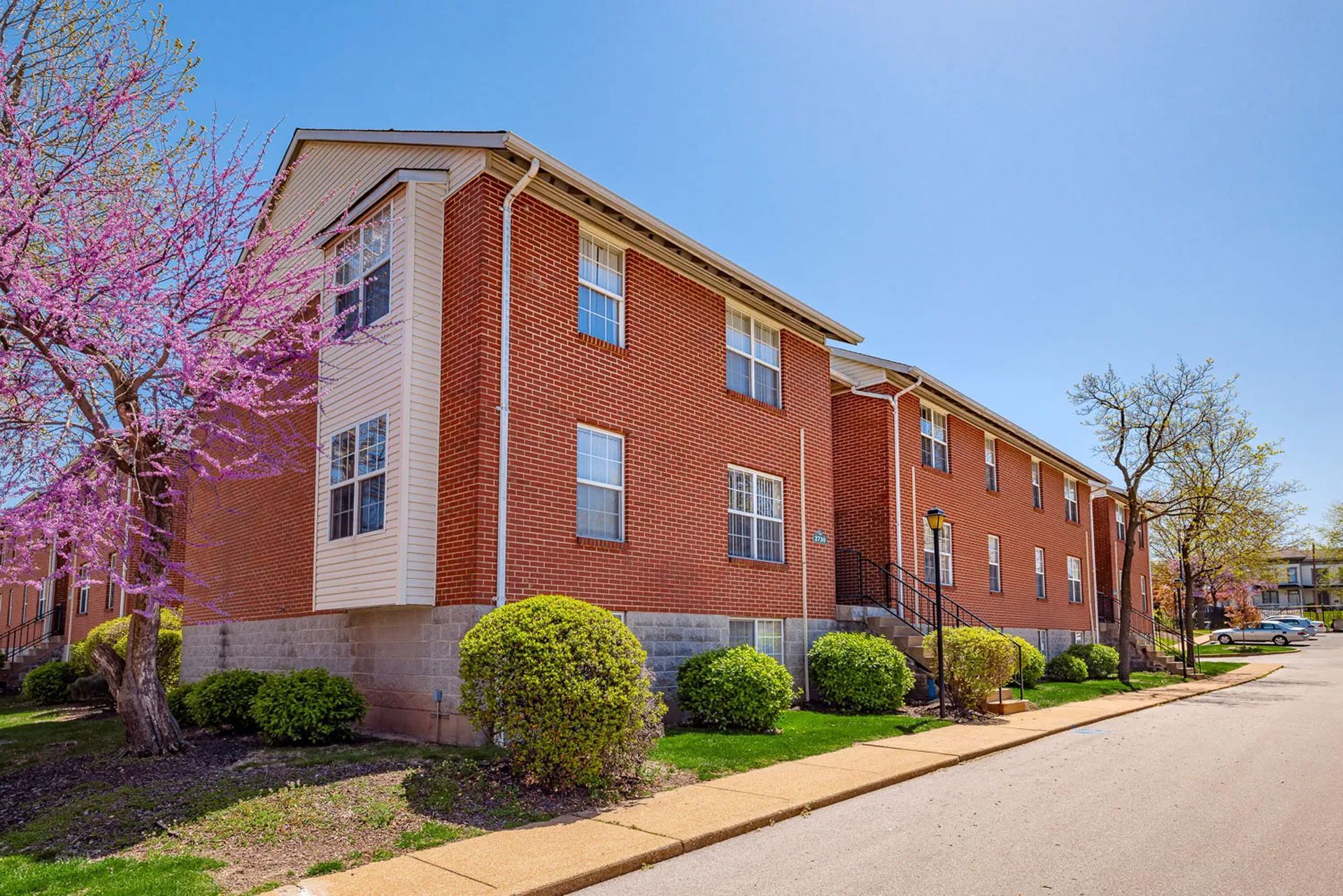 A large brick apartment building with a sidewalk in front of it.
