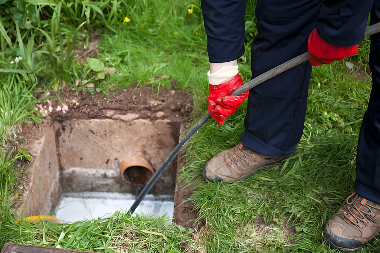 A person is using a hose to clean a drain.
