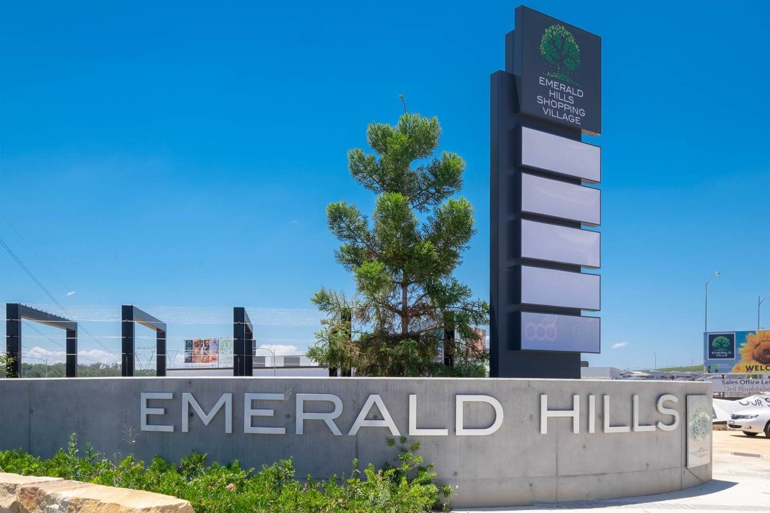Sign for Emerald Hills development with a tall, black sign displaying the name and blank panels, against a blue sky.