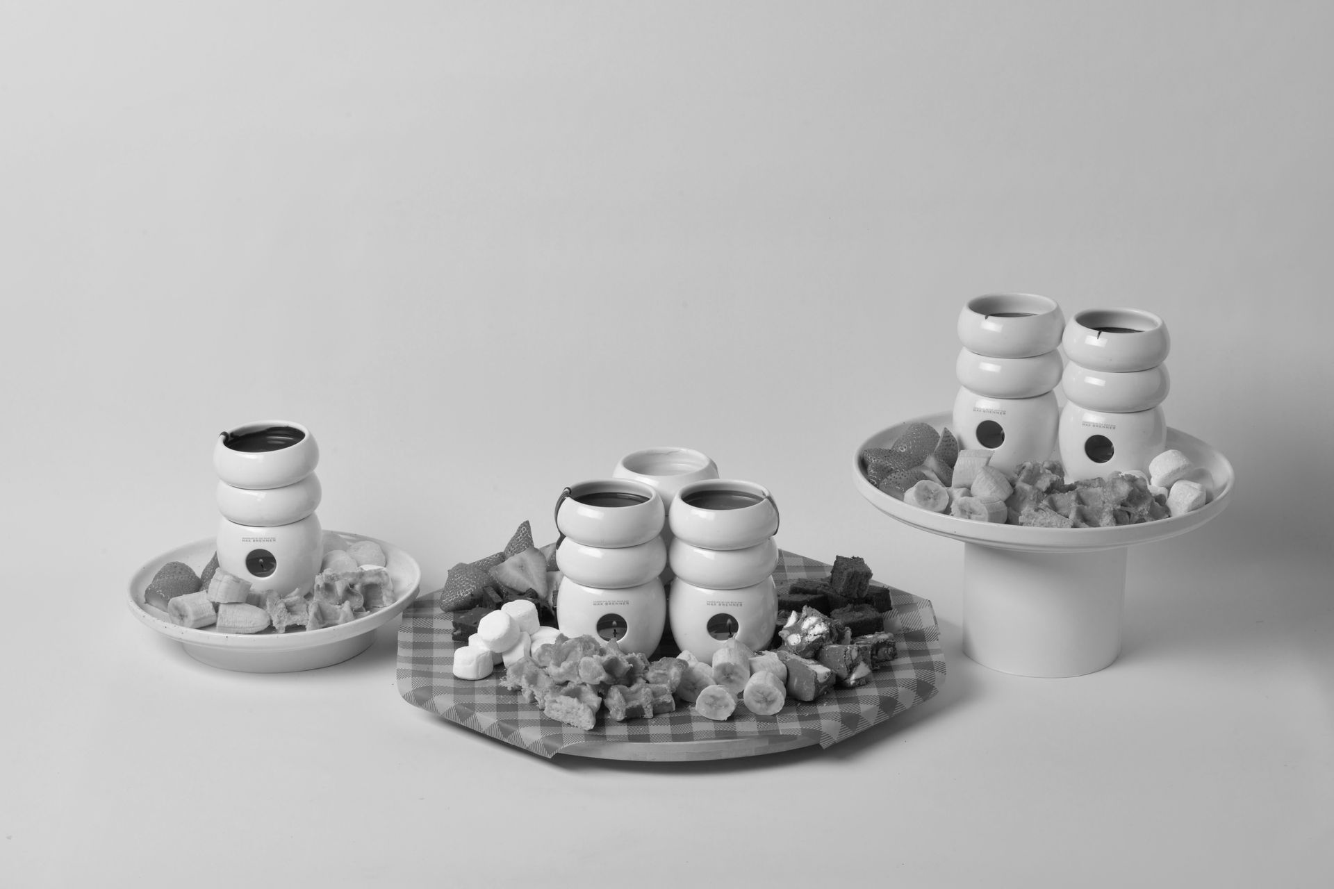Three stacks of small white ceramic cups with dark circles, arranged on trays with decorative items.