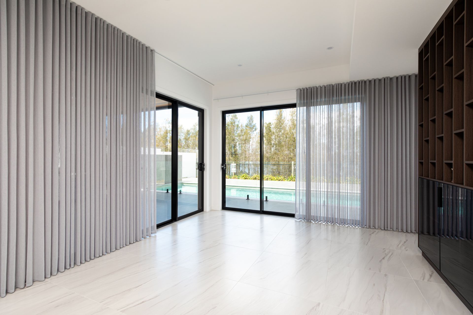 An empty living room with sliding glass doors and curtains.