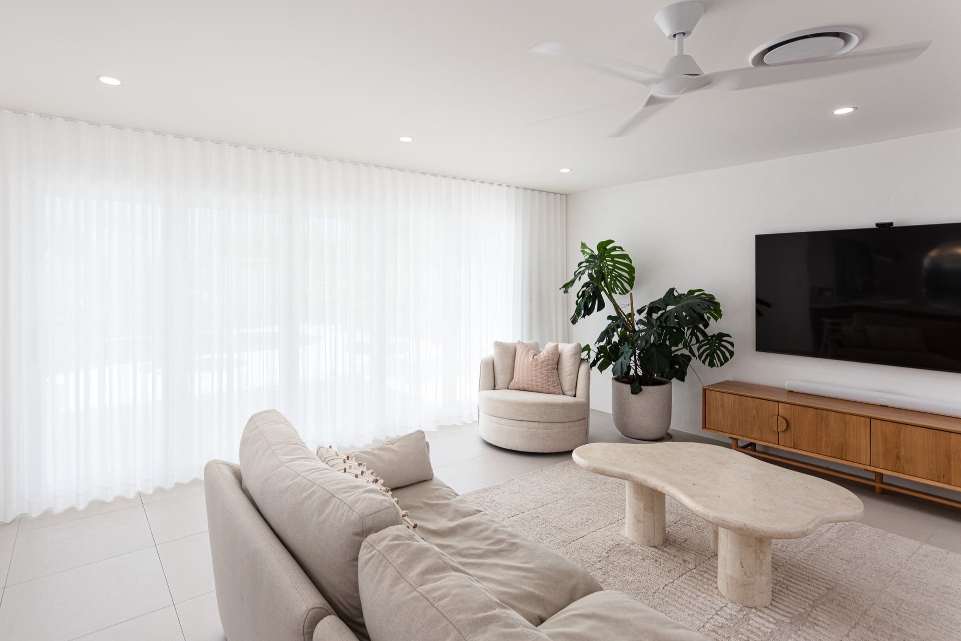 A living room with a couch , chair , coffee table and television.