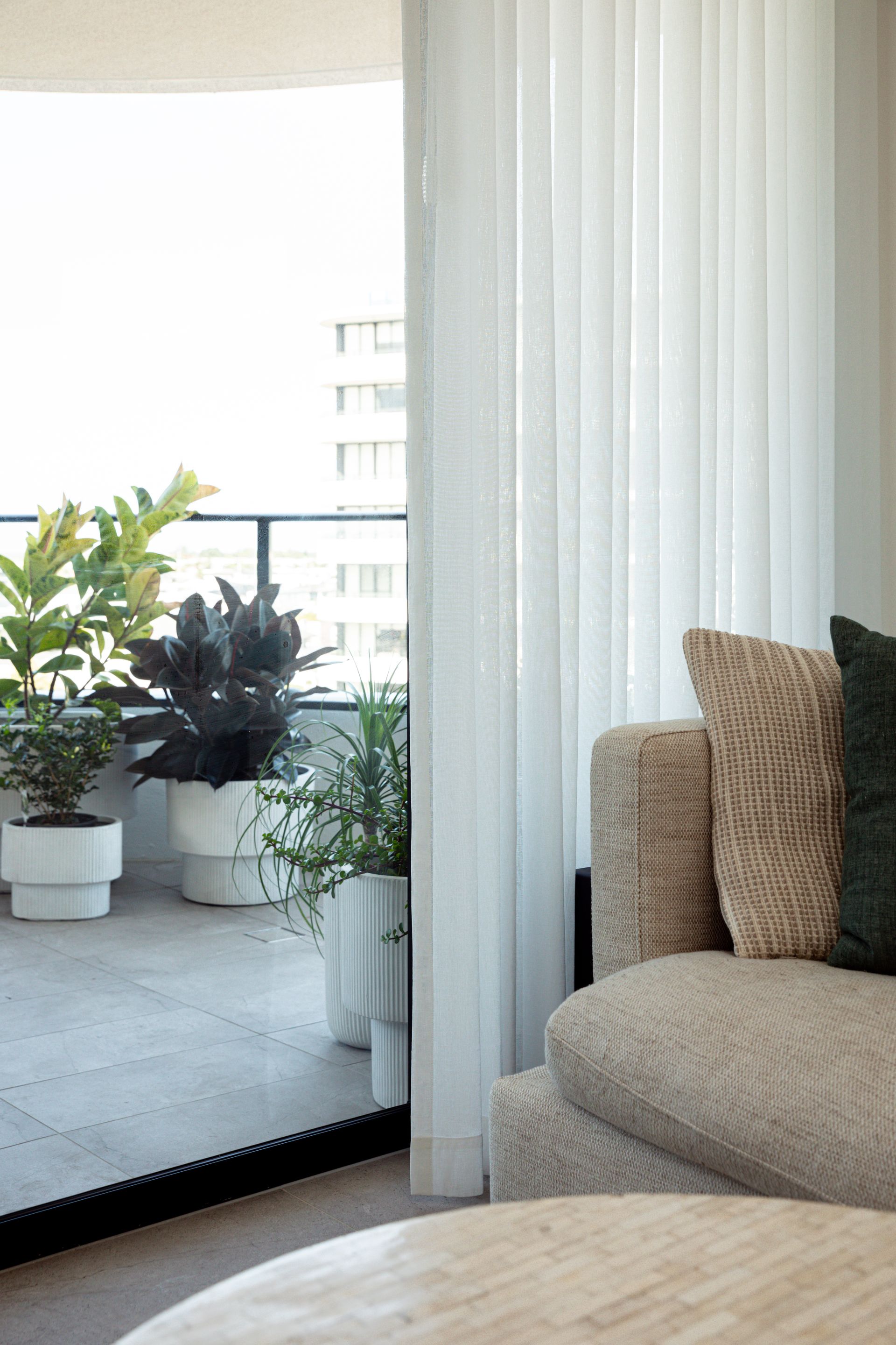 A living room with a couch , table , and potted plants.