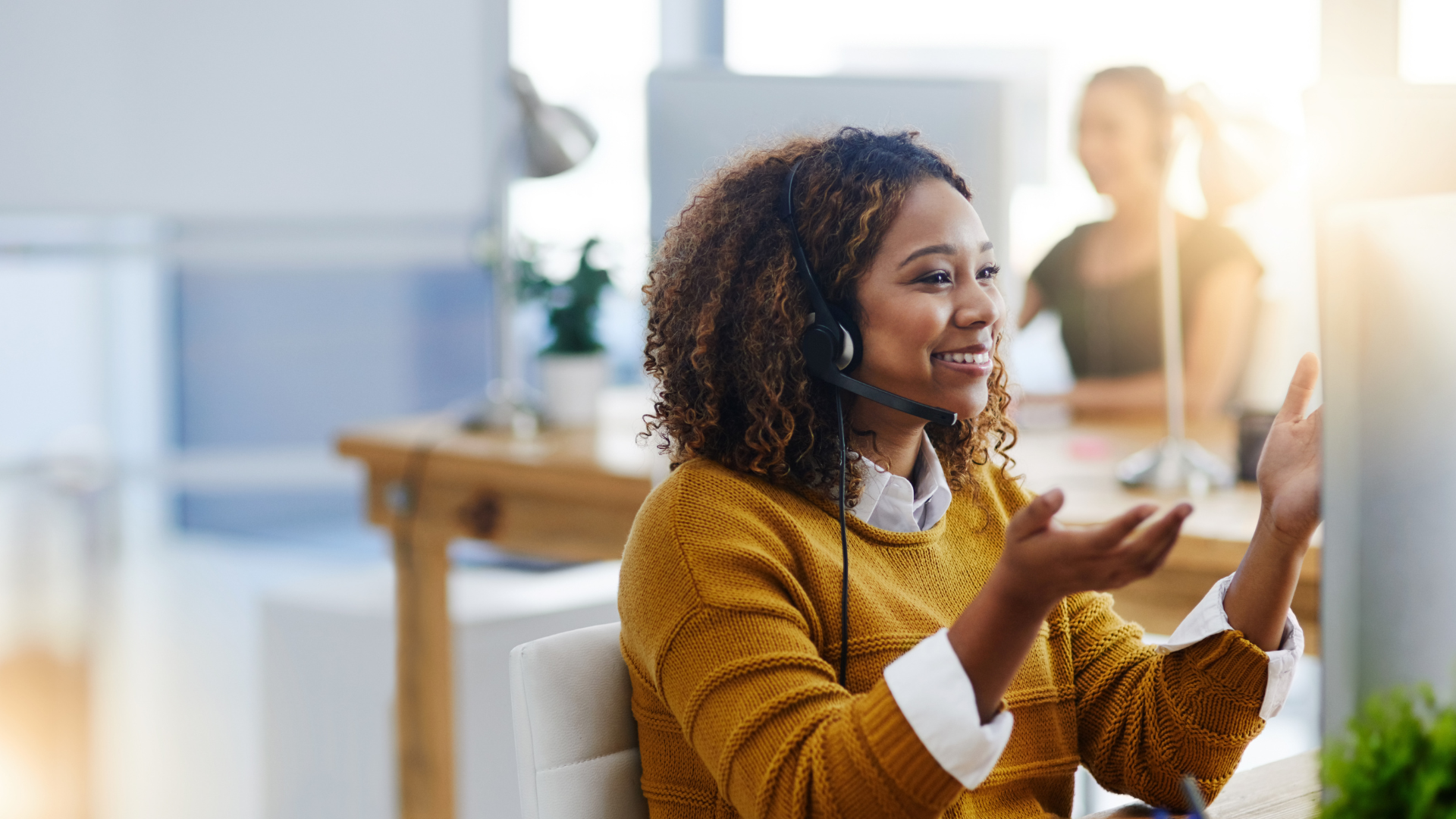 A woman wearing a headset is sitting in front of a computer.
