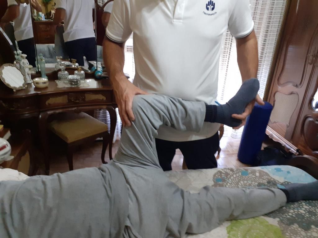 Um homem de camisa branca está esticando a perna de uma pessoa