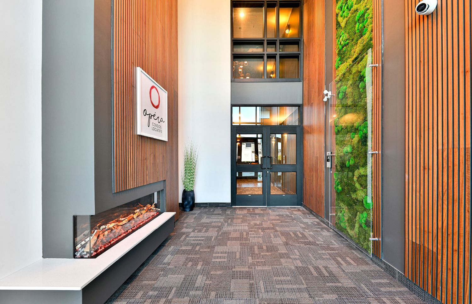 Un couloir dans un immeuble avec une cheminée et un mur végétal.