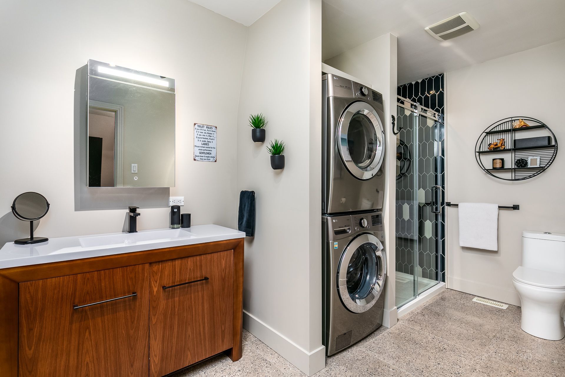 Une salle de bain avec une laveuse et une sécheuse empilées l'une sur l'autre.