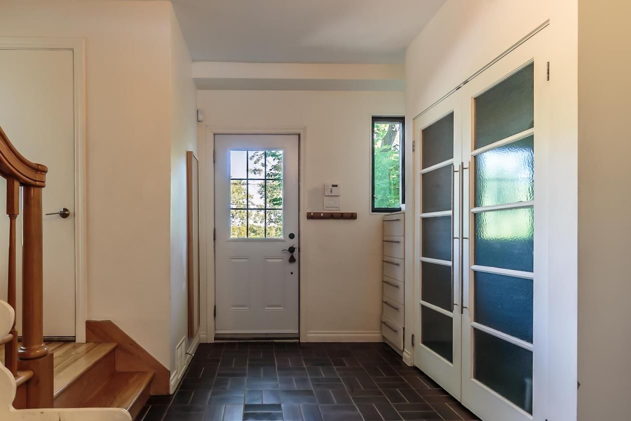Un couloir avec des escaliers et une porte blanche