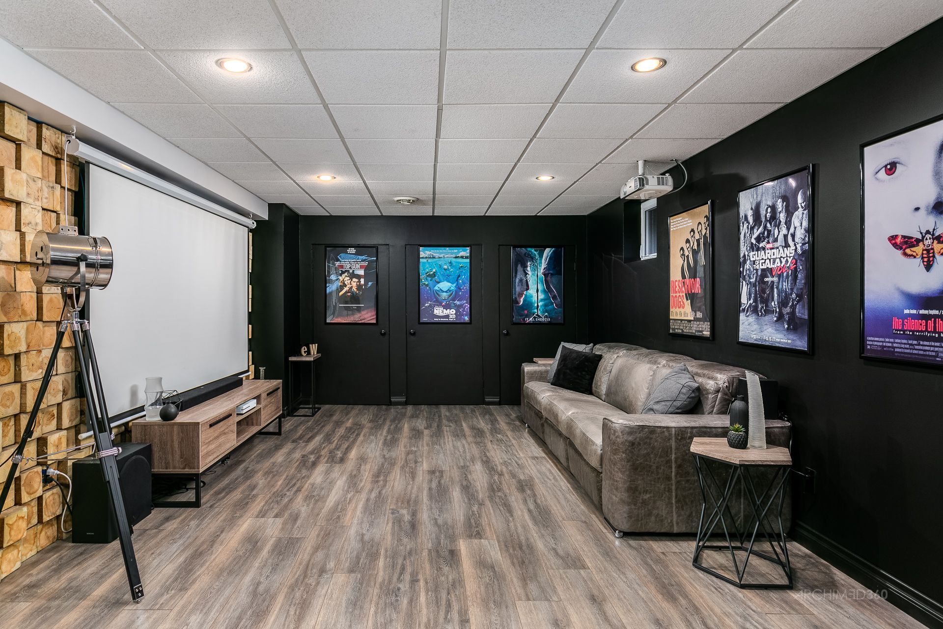 Un salon avec un écran de projection et un canapé.