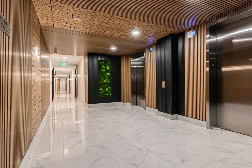 Un long couloir avec ascenseurs dans un immeuble.