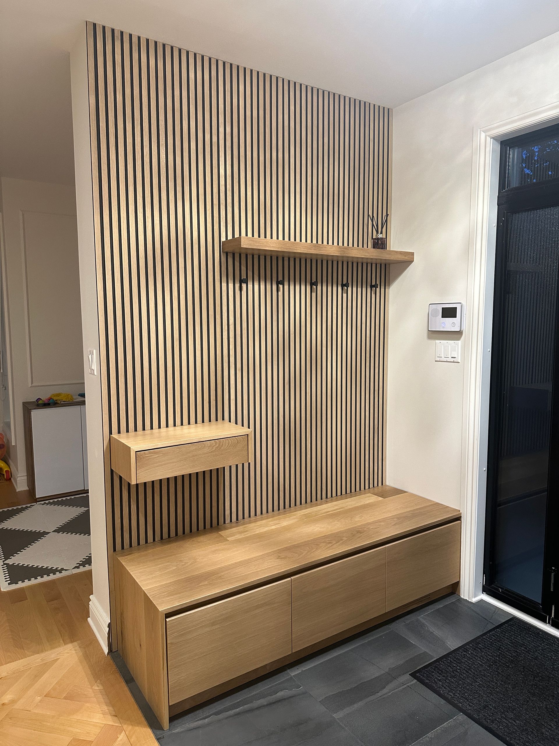 Un banc en bois est assis devant un mur avec du papier peint à rayures.