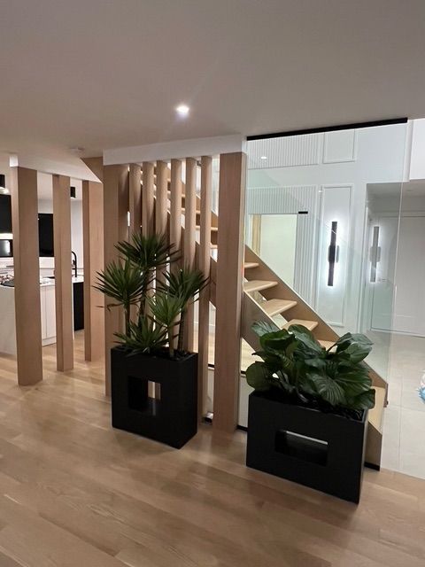 Une pièce avec un escalier et des plantes en pot