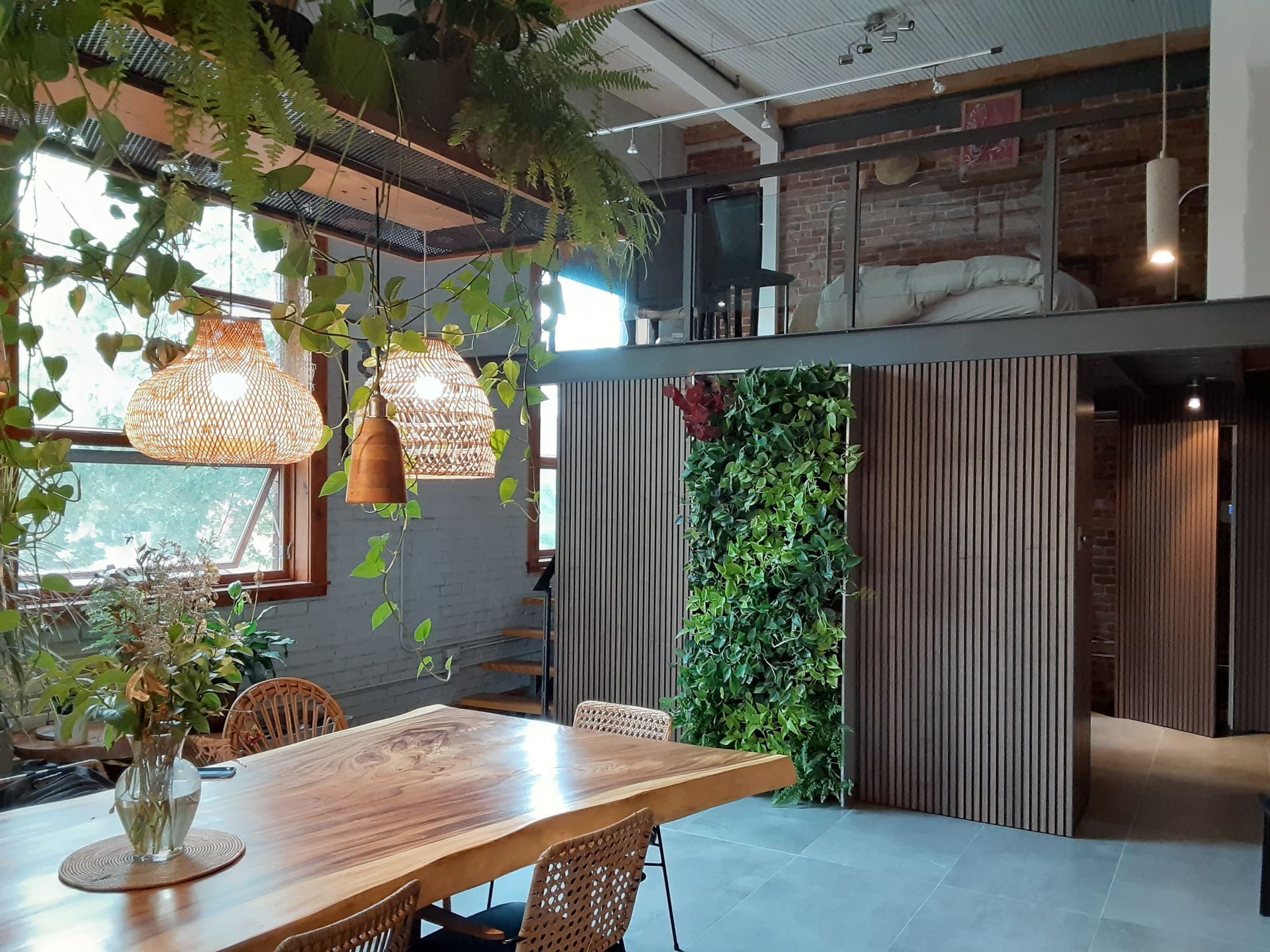 Une salle à manger avec une table et des chaises en bois et un mur végétal.
