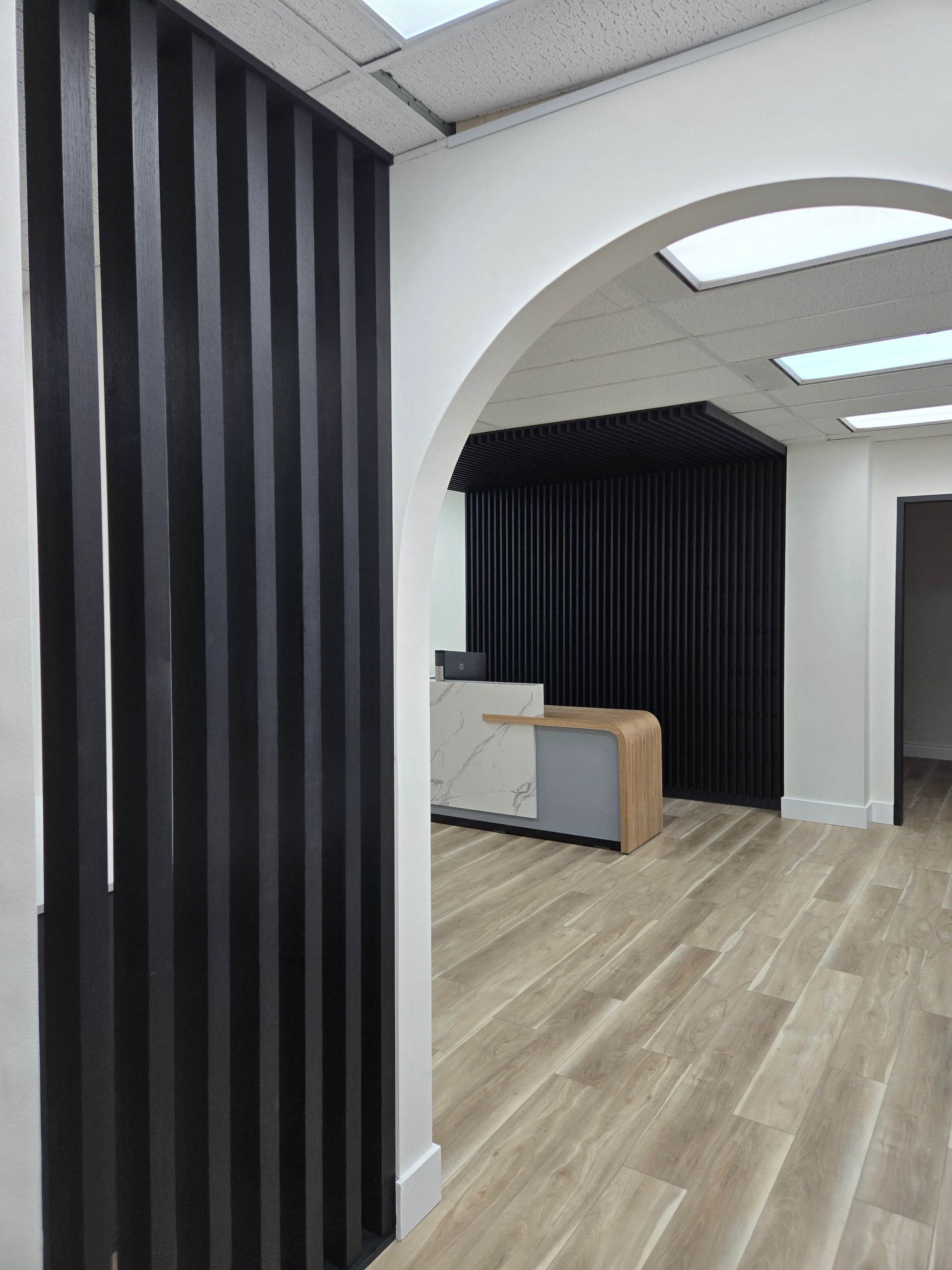 Une pièce avec un plancher en bois et un rideau noir sur le mur.