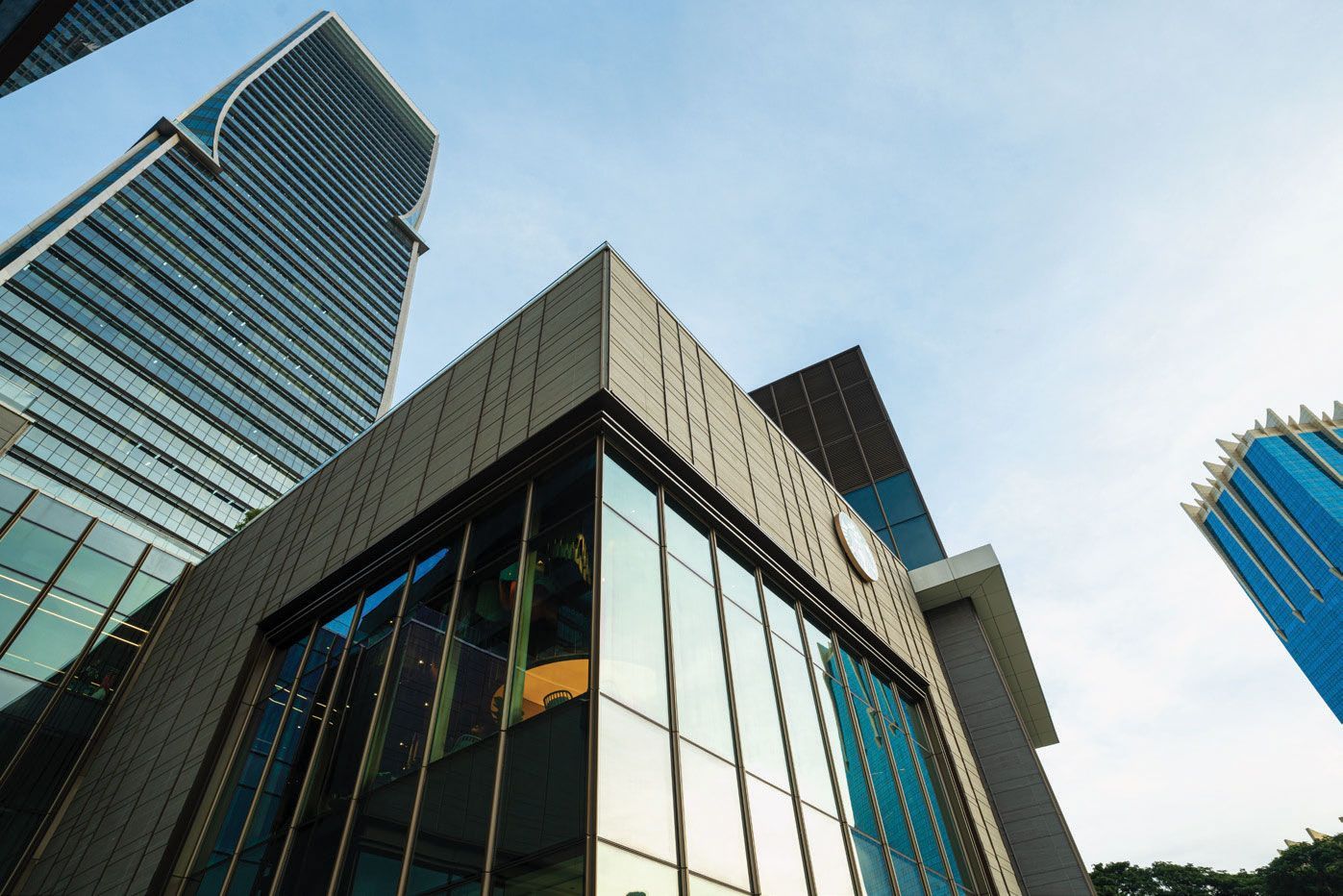 Low-angle view of modern buildings with glass windows against a blue sky.