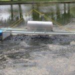 A metal cylinder floats on murky water